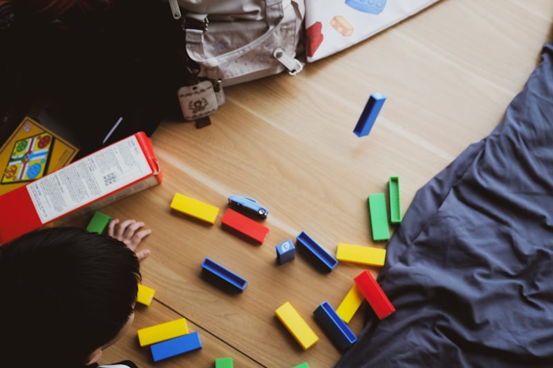 Child playing with colorful building blocks on a warm wooden floor
